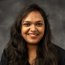 A professional headshot of Shri Rajaram. She has black hair and is wearing a dark business top.